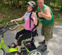 woman riding a trike giving a thumbs up