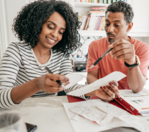 A couple sitting at a desk and reviewing tax documents.