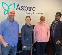 Jessica Cook standing infront of an Aspire logo with three members of the Aspire team.