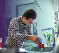 Man washing a red mug in his kitchen.