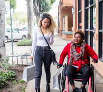 Two women on sidewalk shopping