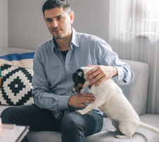 Man petting his small dog on the couch.