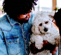 Man holding a small white dog.