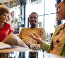 Group of three young professionals sitting at a table having a friendly conversation.