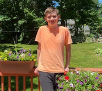 Tim posing outside on a deck surrounded by greenery.
